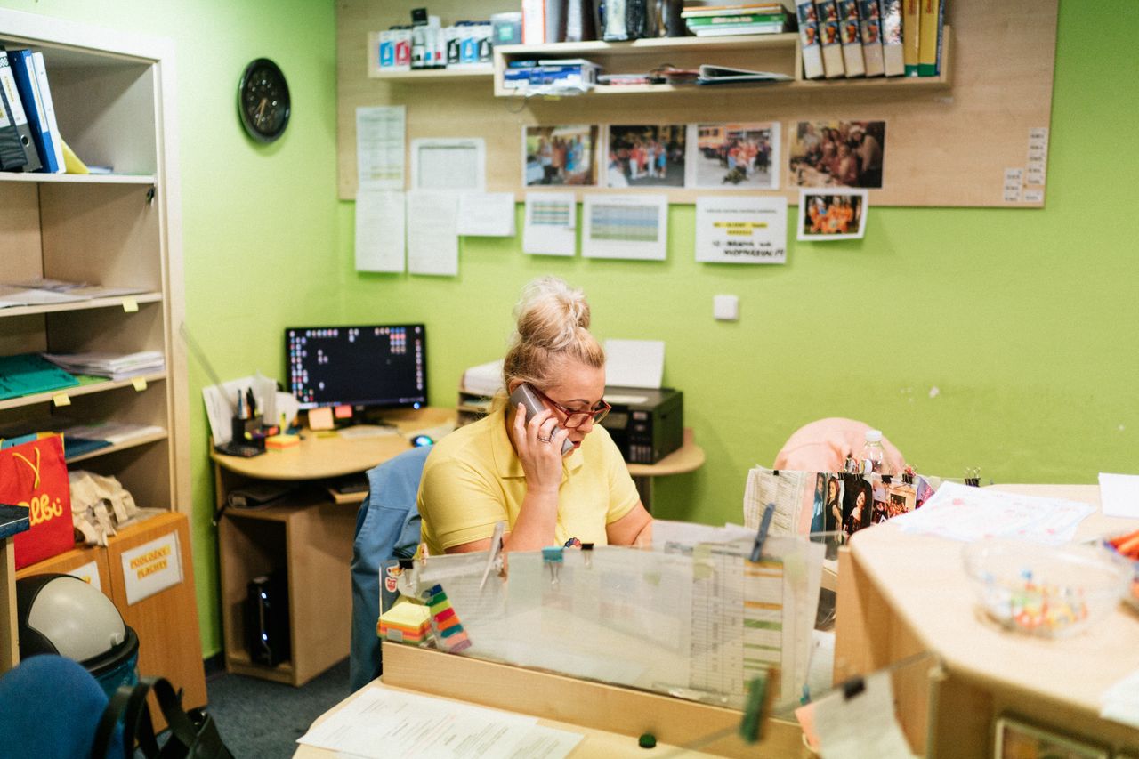 An intake coordinator working at a two-monitor desk beside a stack of faxes — the unglamorous back-office work WaybridgeLabs.AI automates.
